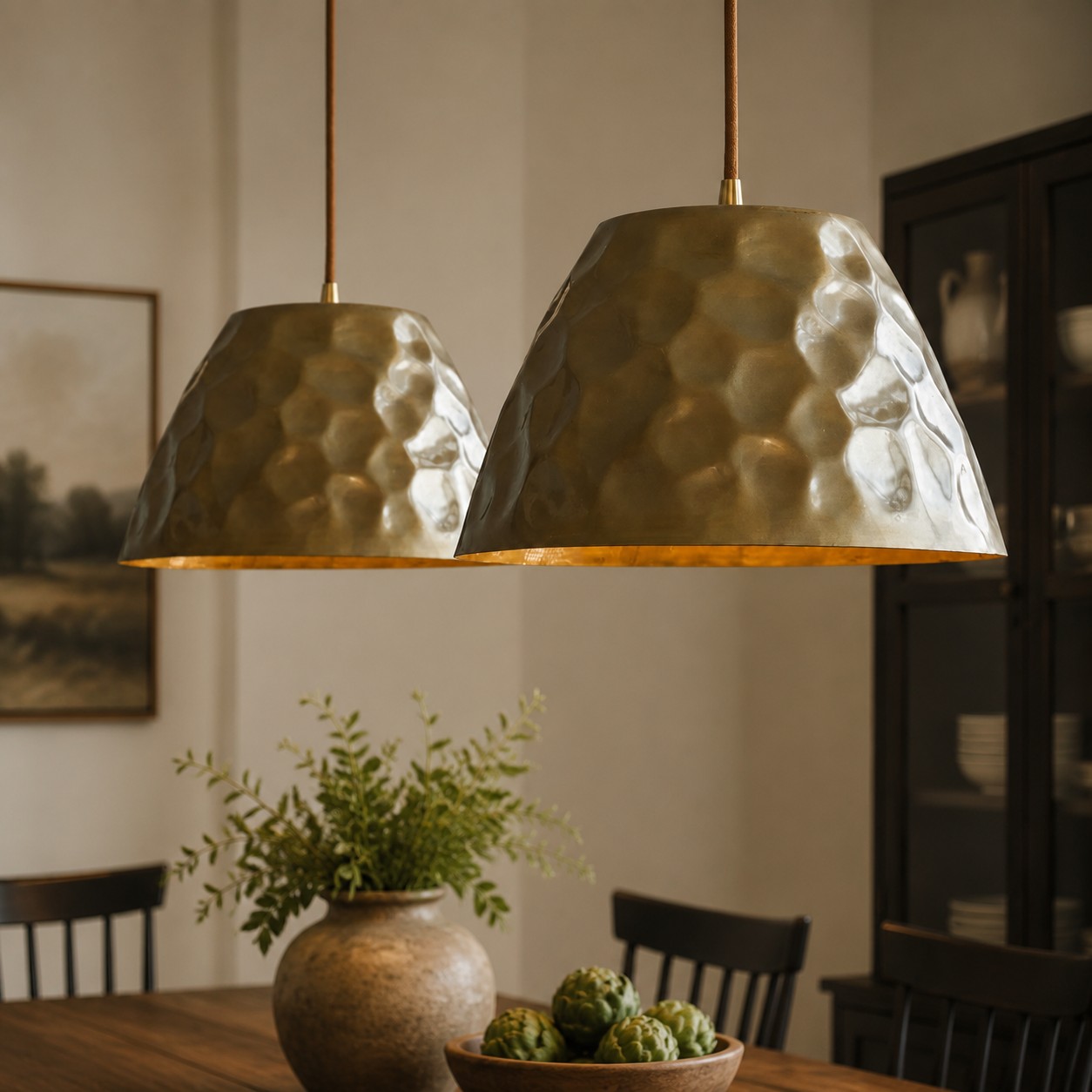 Pair of hammered brass pendant lights above a dining table